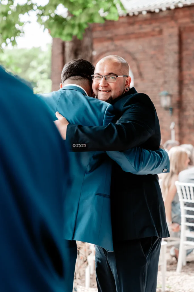 Bräutigam Dennis umarmt einen Freund nach der freien Trauung bei der Hochzeit in Witten.