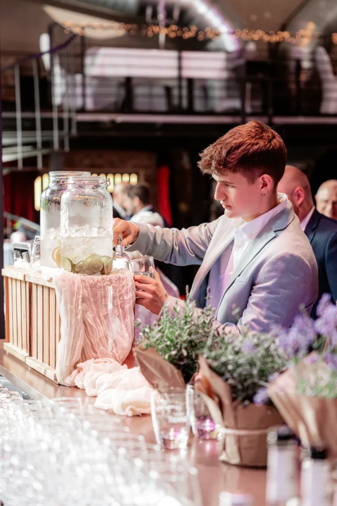 Hochzeitsgast füllt sich Wasser an einem Wasserspender in der Alten Papierfabrik in Wuppertal während einer Hochzeitsfeier ab.